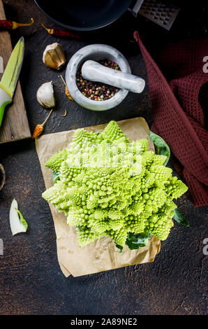 Frais vert, Chou romanesco biologiques crus prête pour la cuisson sur une planche à découper sur fond de bois foncé Banque D'Images