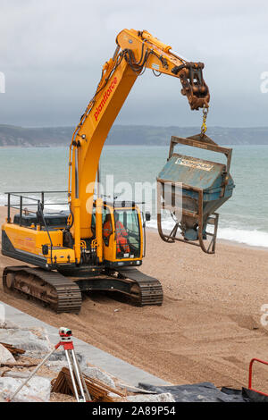 Des ouvriers avec des machines lourdes réparer le mur de protection contre les inondations à Torcross, Devon. Banque D'Images