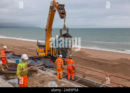 Des ouvriers avec des machines lourdes réparer le mur de protection contre les inondations à Torcross, Devon. Banque D'Images