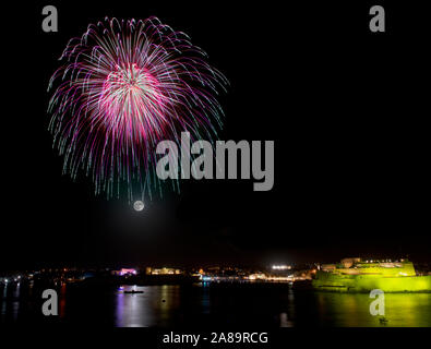 D'artifice explosion de ciel noir avec silhouette ville colorée et refléter sur l'eau Banque D'Images