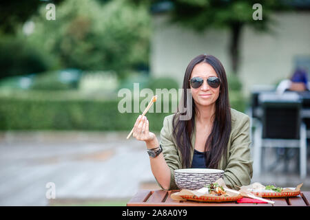 Femme mange l'alimentation de rue au café en plein air dans le parc Banque D'Images