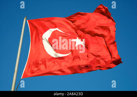 De soie rouge vif, drapeau de la Turquie qui volettent dans le vent contre ciel bleu clair Banque D'Images