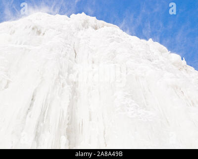 Un haut mur blanc pur de glace et la poudrerie contre un ciel bleu clair Banque D'Images