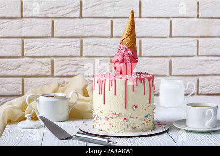 Gâteau d'anniversaire drôle avec de la crème glacée fondue en cornet gaufré et glaçage au goutte à goutte avec un mur de briques à l'arrière-plan Banque D'Images