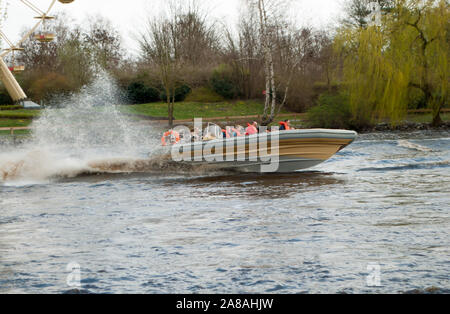 Hodenhagen, Allemagne, le 30 mars 2019 : les gens sur un bateau à moteur en vitesse avec beaucoup d'éclaboussures sur un lac dans un parc de loisirs Banque D'Images