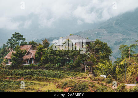 Maisons et maisons sur haut des rizières en terrasses à l'extérieur du magnifique village de Sapa au nord du Vietnam, entourée de montagnes Banque D'Images