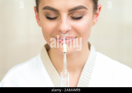 Huile essentielle pour inhalation nasale dans Maholda nez de smiling young woman close up. Banque D'Images