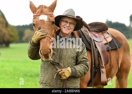 Waldburg, Allemagne. 07Th Nov, 2019. Stellberger Martin, ancien professeur de l'enseignement secondaire, se dresse avec son cheval de Flamenco dans une prairie. Il s'est échappé de la RDA dans le coffre d'une voiture. Environ 20 ans après la chute du Mur de Berlin, le coureur passionné puis s'assit sur son cheval à la balade le long de l'ex-frontière intérieure allemande - environ 1400 kilomètres. Pendant ce temps, le Flamenco est déjà vieux et peut difficilement faire son propriétaire tout plus de crédit : Felix Kästle/dpa/Alamy Live News Banque D'Images