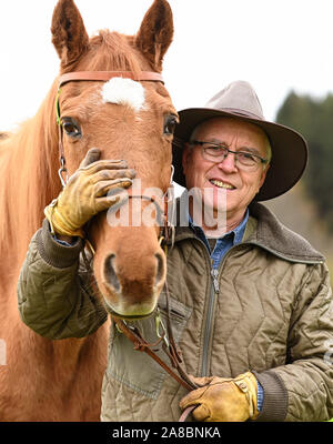 Waldburg, Allemagne. 07Th Nov, 2019. Stellberger Martin, ancien professeur de l'enseignement secondaire, se dresse avec son cheval de Flamenco dans une prairie. Il s'est échappé de la RDA dans le coffre d'une voiture. Environ 20 ans après la chute du Mur de Berlin, le coureur passionné puis s'assit sur son cheval à la balade le long de l'ex-frontière intérieure allemande - environ 1400 kilomètres. Pendant ce temps, le Flamenco est déjà vieux et peut difficilement faire son propriétaire tout plus de crédit : Felix Kästle/dpa/Alamy Live News Banque D'Images