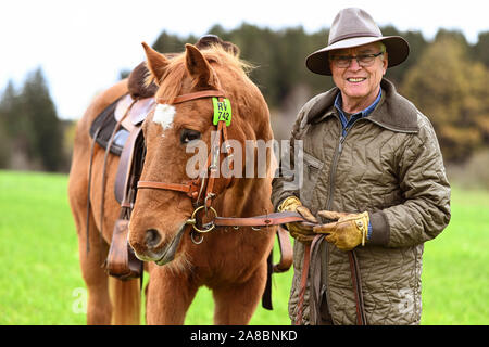 Waldburg, Allemagne. 07Th Nov, 2019. Stellberger Martin, ancien professeur de l'enseignement secondaire, se dresse avec son cheval de Flamenco dans une prairie. Il s'est échappé de la RDA dans le coffre d'une voiture. Environ 20 ans après la chute du Mur de Berlin, le coureur passionné puis s'assit sur son cheval à la balade le long de l'ex-frontière intérieure allemande - environ 1400 kilomètres. Pendant ce temps, le Flamenco est déjà vieux et peut difficilement faire son propriétaire tout plus de crédit : Felix Kästle/dpa/Alamy Live News Banque D'Images