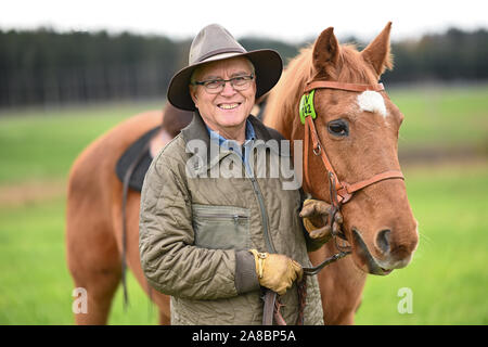 Waldburg, Allemagne. 07Th Nov, 2019. Stellberger Martin, ancien professeur de l'enseignement secondaire, se dresse avec son cheval de Flamenco dans une prairie. Il s'est échappé de la RDA dans le coffre d'une voiture. Environ 20 ans après la chute du Mur de Berlin, le coureur passionné puis s'assit sur son cheval à la balade le long de l'ex-frontière intérieure allemande - environ 1400 kilomètres. Pendant ce temps, le Flamenco est déjà vieux et peut difficilement faire son propriétaire tout plus de crédit : Felix Kästle/dpa/Alamy Live News Banque D'Images