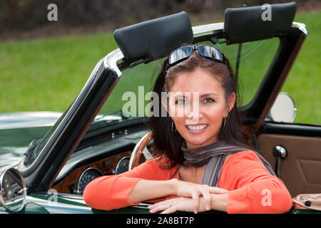 Junge Frau blickt entspannt aus einem Triumph TR6 So Close. Banque D'Images