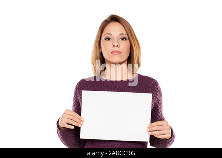 Jeune femme sérieuse tenant une feuille de papier vierge pour la publicité Banque D'Images