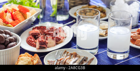 Bannière d'alcool ouzo grec, deux verres et des fruits de mer meze hors-d'arrière-plan, vue rapprochée Banque D'Images