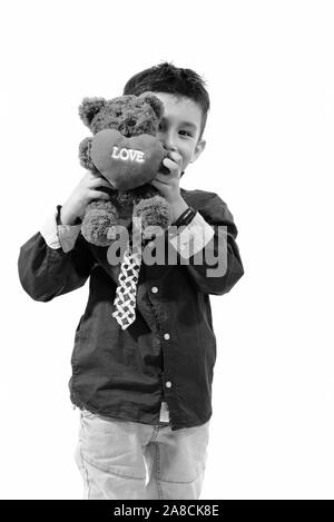 Studio shot of cute boy Hiding behind ours en peluche avec coeur et amour sign Banque D'Images