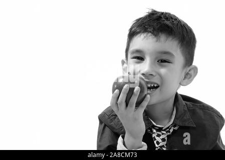 Studio shot of cute happy boy smiling and eating apple Banque D'Images