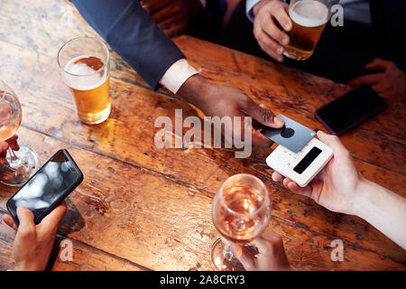 Close Up of Businessman Paying for Round de boissons dans un bar après le travail à l'aide d'une carte sans contact Banque D'Images