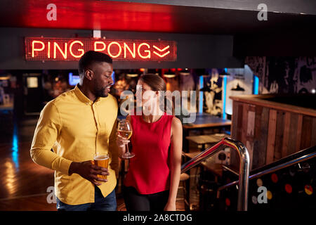 Couple sur la date monter les escaliers qu'ils répondent pour prendre un verre et socialiser dans Bar Banque D'Images