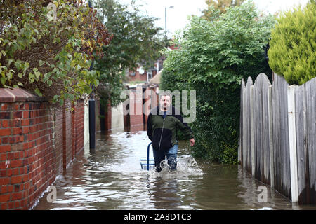 Un homme marche à travers l'eau d'inondation dans la région de Doncaster, dans le Yorkshire, comme certaines parties de l'Angleterre a connu un mois de pluie en 24 heures, avec des dizaines de personnes secourues ou forcés d'évacuer leurs maisons, d'autres coincés la nuit dans un centre commercial et des plans de voyage jeté dans le chaos. Banque D'Images