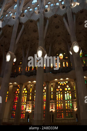 Sagrada Familia - intérieur. Rangées de grands vitraux de couleurs chaudes et de hauts piliers. Banque D'Images