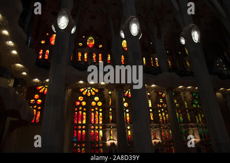 Sagrada Familia - intérieur. Rangées de grands vitraux de couleurs chaudes et de hauts piliers. Banque D'Images
