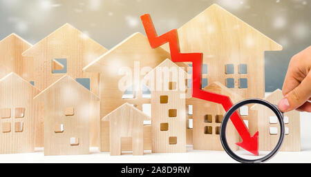 Maisons en bois miniature et flèche vers le bas. La notion de logement à faible demande. Des remises pour l'immobilier à l'hiver. Prêt hypothécaire, prêt. À peu de frais. Le Christ Banque D'Images