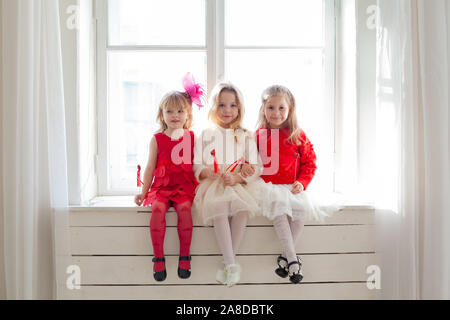 Trois magnifiques petites filles en robes rouges et blancs à la fête Banque D'Images