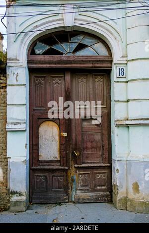 Porte en bois double en arc délabrée avec façade de verre cassée en haut comme une rue à l'entrée d'un vieux bâtiment dans une vue en gros plan Banque D'Images