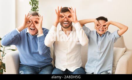 Grand-père, père et fils Holding doigts près yeux séance piscine Banque D'Images