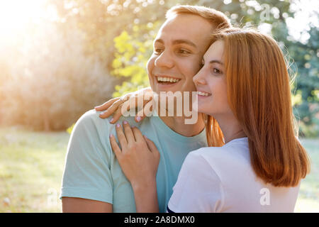 Jeune couple à l'extérieur. Jolie fille aux cheveux rouges et beau boy hugging ensemble. Banque D'Images