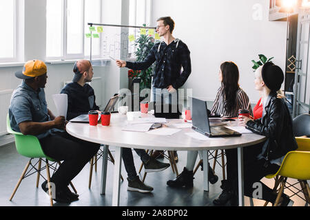 Groupe d'affaires habillé décontracté discuter des idées de l'office. Les créatifs se sont réunis à la table de réunion pour discuter de la Banque D'Images