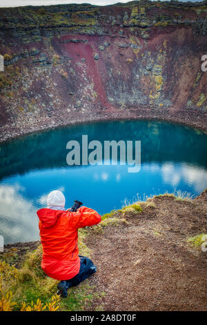 Photographe en veste rouge à cratère Kerid en Islande Banque D'Images