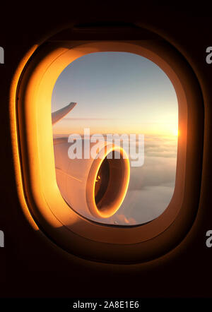 Magnifique coucher de soleil vu à travers une fenêtre de l'avion avec le moteur et l'aile de l'avion à réaction visible. Banque D'Images