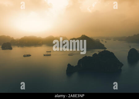 Image aérienne de la Baie d'Ha Long pendant le lever du soleil en automne 2019 avec les navires de croisière et indésirable bateaux ancrés dans les baies Banque D'Images