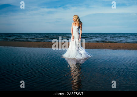 Portrait of young blonde bride restant entre l'eau, à la recherche sur le côté Banque D'Images