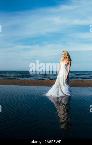 Portrait of young blonde bride restant entre l'eau, à la recherche sur le côté Banque D'Images