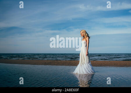 Portrait of young blonde bride restant entre l'eau, les yeux fermés Banque D'Images