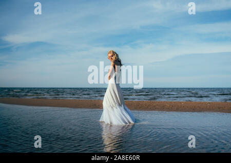 Portrait of young blonde bride restant entre l'eau, les yeux fermés Banque D'Images