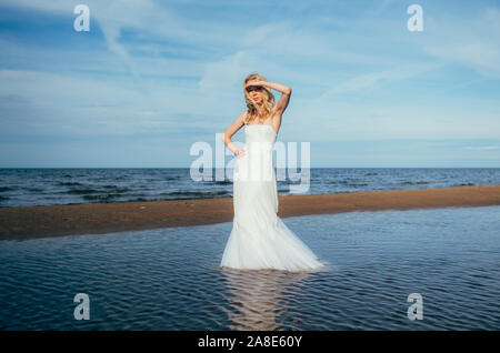 Portrait of young blonde bride restant entre l'eau, à la recherche de l'appareil photo Banque D'Images