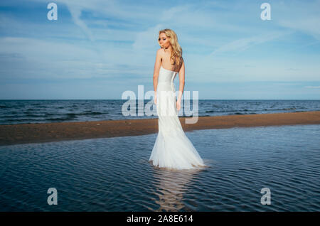 Portrait of young blonde bride restant entre l'eau, à la recherche de l'appareil photo Banque D'Images