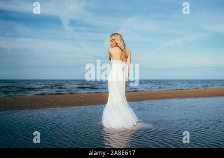 Portrait of young blonde bride restant entre l'eau, les yeux fermés Banque D'Images