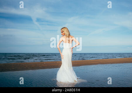 Portrait of young blonde bride restant entre l'eau, regardant vers le bas Banque D'Images