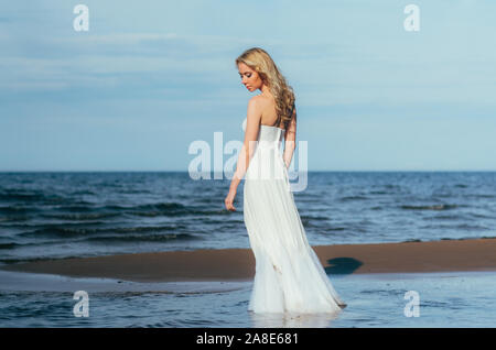 Portrait of young blonde bride restant entre l'eau, regardant vers le bas Banque D'Images