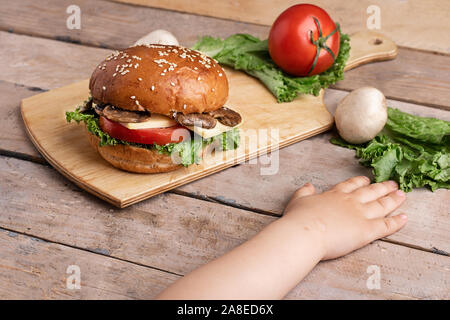 Enfants mains près de mushroom burger, table en bois Banque D'Images