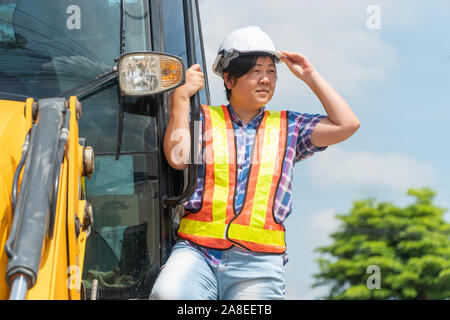 L'Asian female engineer sont debout sur la pelleteuse et se leva en regardant vers le site de construction Le concept de l'égalité de capacité entre les hommes et les femm Banque D'Images
