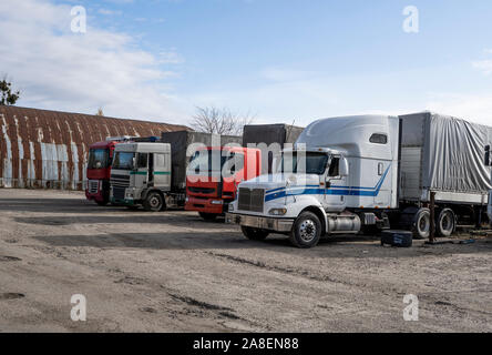 Camions modernes de diverses couleurs et modèles sont impliqués pour le transport de différents types de marchandises commerciales sont dans une rangée sur l'arrêt de camion dans Banque D'Images