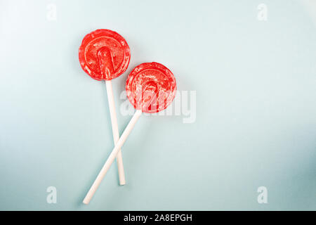En forme de rond doux rouge lollipops savoureux sur fond bleu pastel. Copy space Banque D'Images