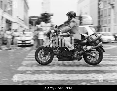 Un homme d'affaires sur un triporteur motorisé accélère rapidement par l'heure de pointe à Rome, Italie Banque D'Images