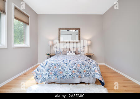 Un lit centré dans la chambre principale d'une résidence avec deux lampes  sur la table de chevet et un miroir est suspendu au-dessus du lit Photo  Stock - Alamy
