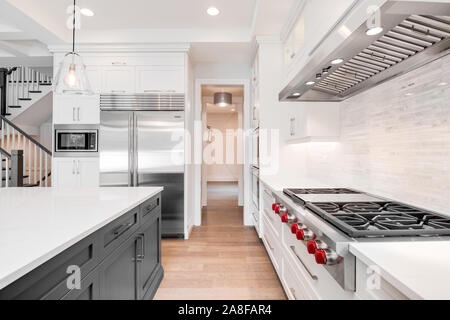 Une luxueuse cuisine moderne avec des appareils en acier inoxydable loup blanc entouré de belles armoires, granite et planchers de bois. Banque D'Images